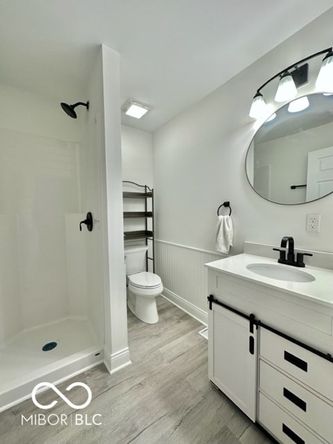 bathroom featuring hardwood / wood-style floors, vanity, toilet, and walk in shower