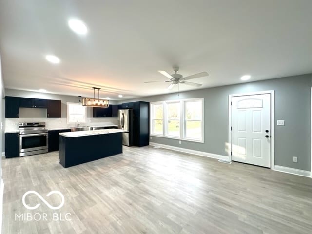 kitchen featuring a center island, hanging light fixtures, stainless steel appliances, light hardwood / wood-style floors, and ceiling fan with notable chandelier