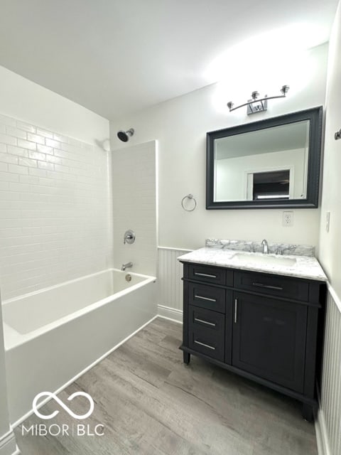 bathroom featuring hardwood / wood-style floors, vanity, and tiled shower / bath