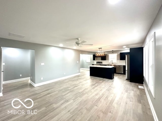 kitchen featuring a center island, sink, ceiling fan, light wood-type flooring, and appliances with stainless steel finishes