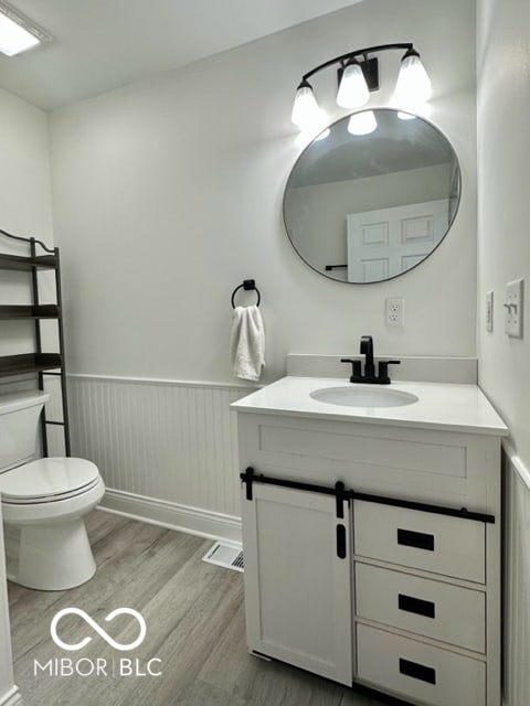 bathroom with wood-type flooring, vanity, and toilet