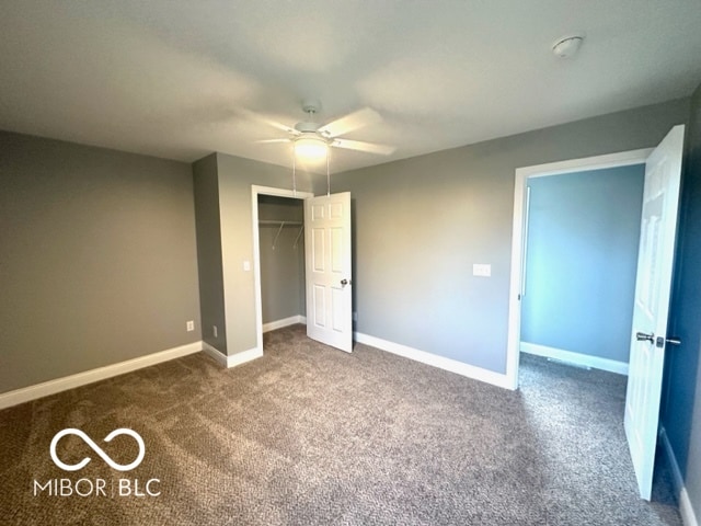 unfurnished bedroom featuring dark colored carpet, a closet, and ceiling fan