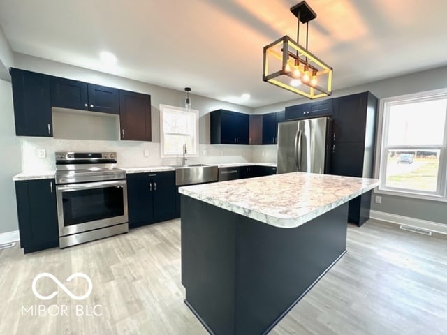 kitchen featuring decorative light fixtures, a kitchen island, sink, and appliances with stainless steel finishes