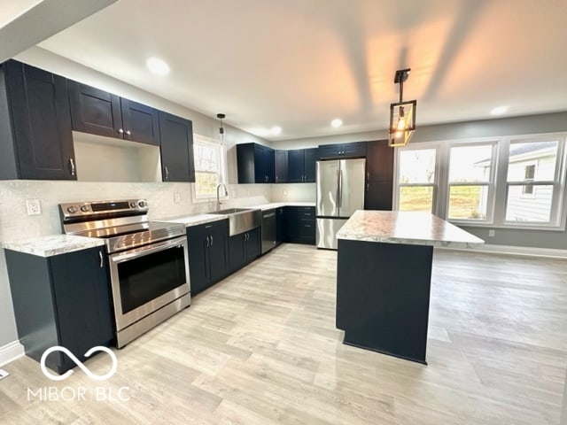 kitchen featuring a center island, decorative light fixtures, a healthy amount of sunlight, and appliances with stainless steel finishes