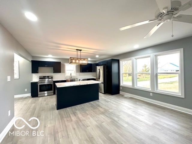 kitchen featuring stainless steel appliances, ceiling fan, light hardwood / wood-style floors, a kitchen island, and hanging light fixtures