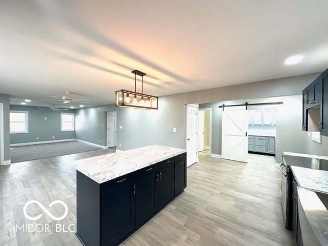 kitchen featuring ceiling fan, a center island, hanging light fixtures, a barn door, and stainless steel electric range