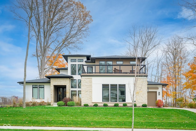 view of front facade with a balcony, a front yard, and a garage