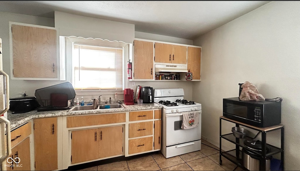 kitchen featuring white range with gas stovetop, sink, and light tile patterned floors