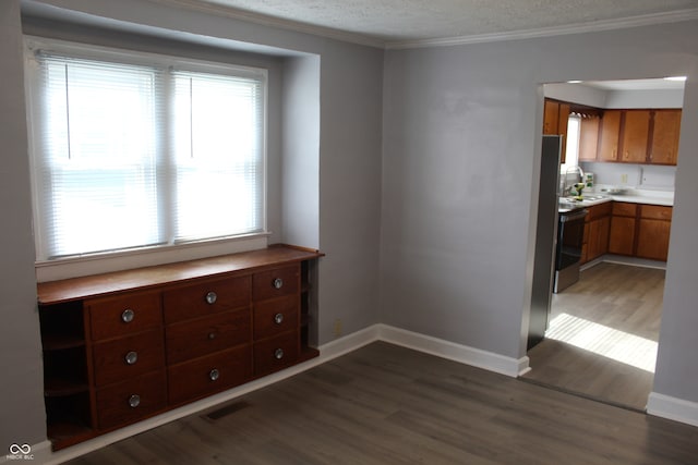 unfurnished dining area featuring a textured ceiling, sink, ornamental molding, and dark wood-type flooring