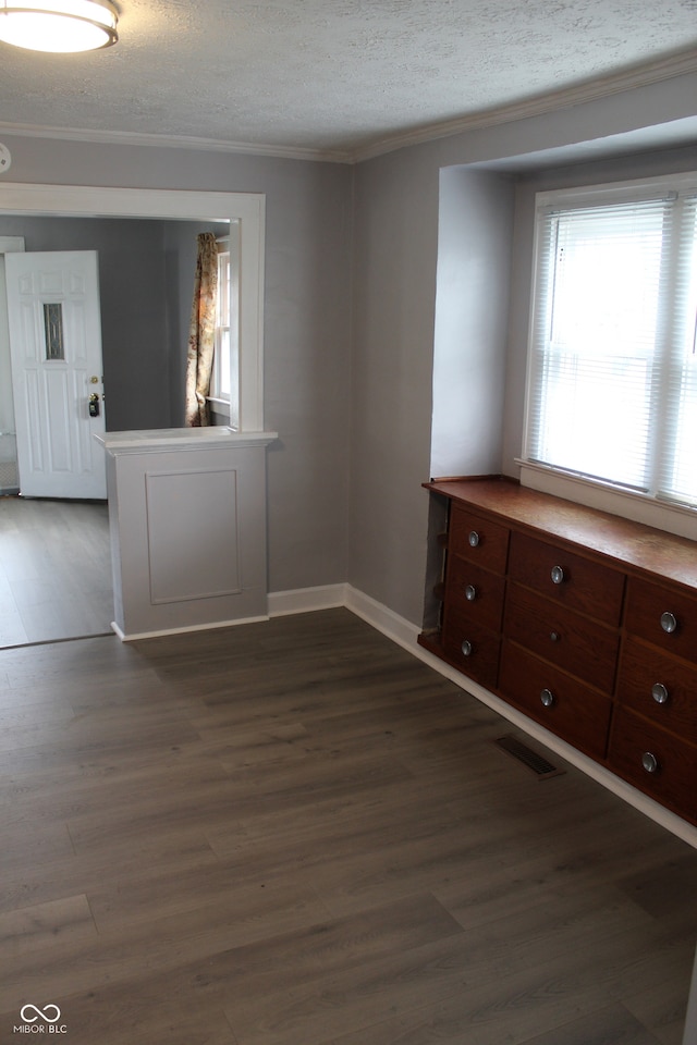 unfurnished room with dark hardwood / wood-style floors, ornamental molding, and a textured ceiling