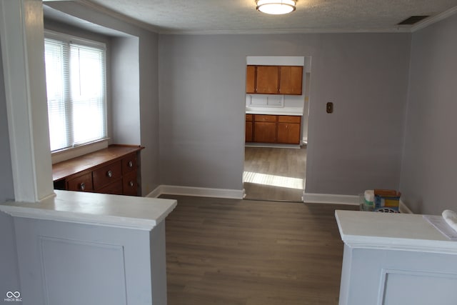 unfurnished dining area with dark hardwood / wood-style floors, crown molding, and a textured ceiling