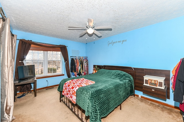 carpeted bedroom with ceiling fan and a textured ceiling