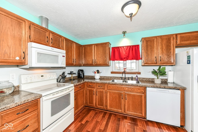 kitchen with white appliances, sink, dark stone countertops, a textured ceiling, and dark hardwood / wood-style flooring