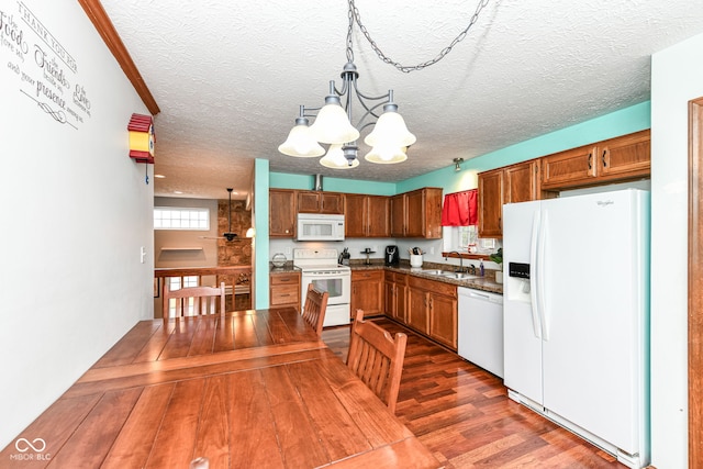 kitchen featuring white appliances, dark wood-type flooring, sink, pendant lighting, and an inviting chandelier