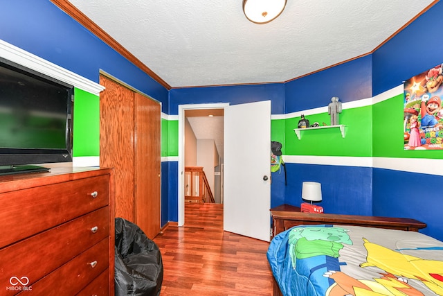 bedroom with wood-type flooring, a textured ceiling, and crown molding