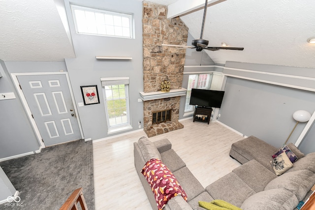 living room with a textured ceiling, ceiling fan, beam ceiling, a fireplace, and hardwood / wood-style floors