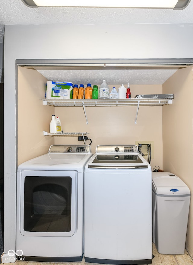 clothes washing area featuring washing machine and dryer and a textured ceiling