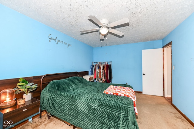 bedroom featuring ceiling fan, light colored carpet, and a textured ceiling