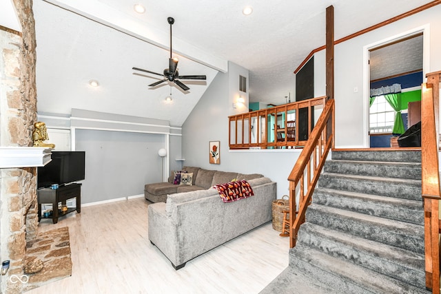 living room with ceiling fan, lofted ceiling with beams, wood-type flooring, a textured ceiling, and a fireplace