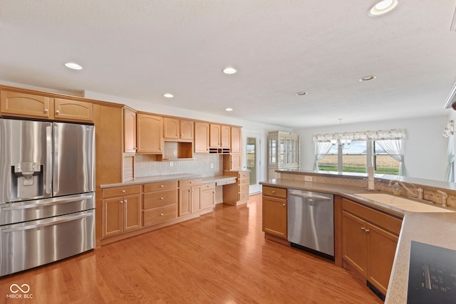 kitchen featuring backsplash, stainless steel appliances, light hardwood / wood-style floors, and sink