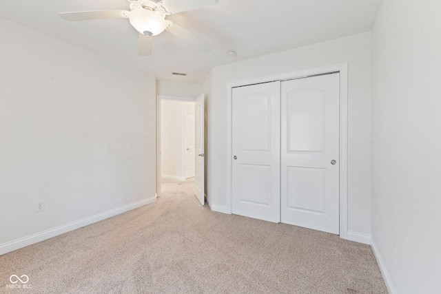 unfurnished bedroom with light carpet, a closet, and ceiling fan