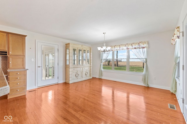 unfurnished dining area featuring a chandelier and light wood-type flooring