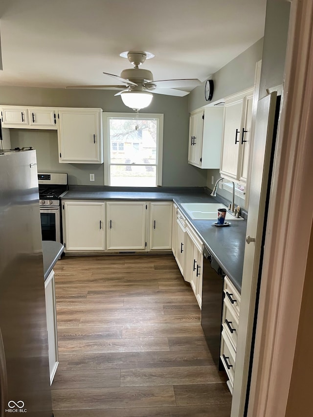 kitchen featuring appliances with stainless steel finishes, ceiling fan, sink, white cabinets, and hardwood / wood-style floors