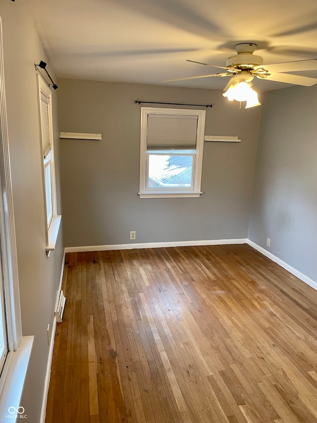 empty room featuring baseboard heating, ceiling fan, and light wood-type flooring