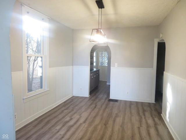 unfurnished dining area with dark wood-type flooring and a wealth of natural light