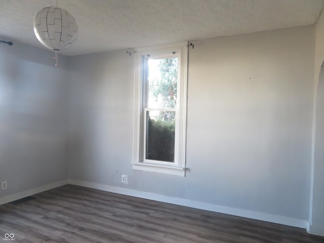 unfurnished room featuring dark wood-type flooring and a textured ceiling