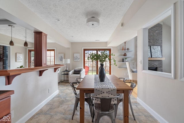 dining area featuring a textured ceiling and a brick fireplace