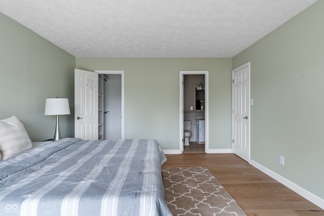 unfurnished bedroom with ensuite bath, wood-type flooring, and a textured ceiling