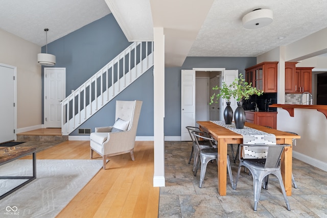 dining room with a textured ceiling, light wood-type flooring, and sink