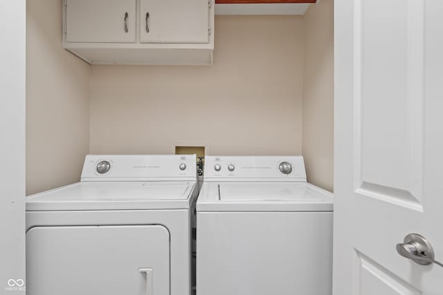 washroom with washing machine and clothes dryer and cabinets