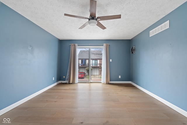 unfurnished room with ceiling fan, light wood-type flooring, and a textured ceiling