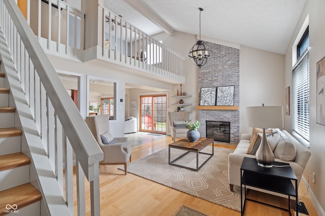 living room with beam ceiling, high vaulted ceiling, a chandelier, wood-type flooring, and a fireplace