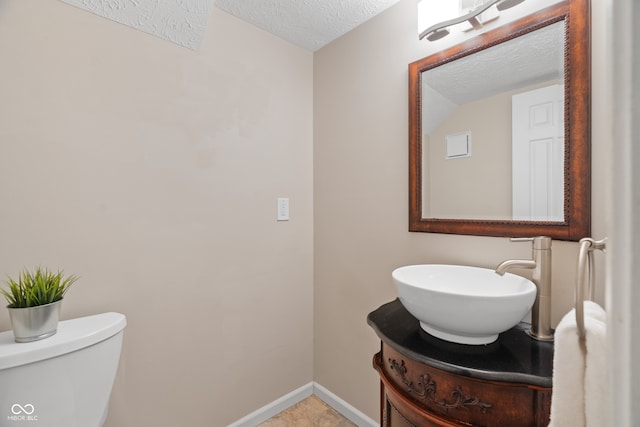 bathroom featuring vanity, a textured ceiling, and toilet