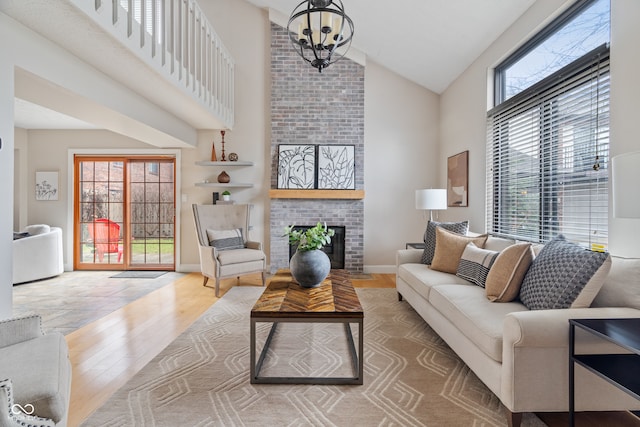 living room with a fireplace, high vaulted ceiling, wood-type flooring, and a notable chandelier