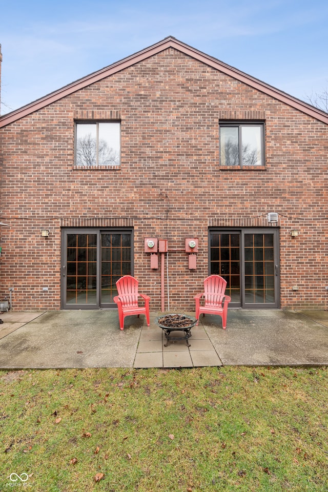 back of property with a fire pit, a patio area, and a yard