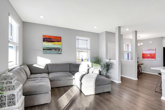 living room with dark hardwood / wood-style floors, an inviting chandelier, and a wealth of natural light