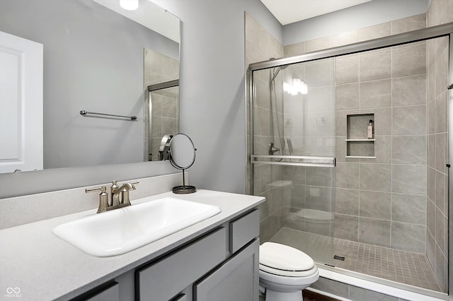 bathroom featuring an enclosed shower, vanity, and toilet