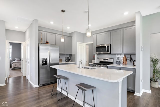 kitchen with pendant lighting, dark wood-type flooring, sink, gray cabinets, and appliances with stainless steel finishes