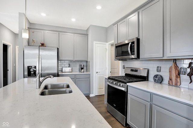 kitchen featuring appliances with stainless steel finishes, gray cabinetry, pendant lighting, and sink