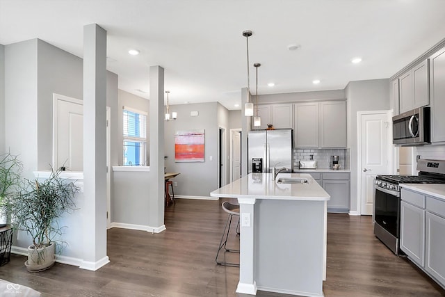 kitchen featuring dark hardwood / wood-style floors, gray cabinets, an island with sink, and appliances with stainless steel finishes