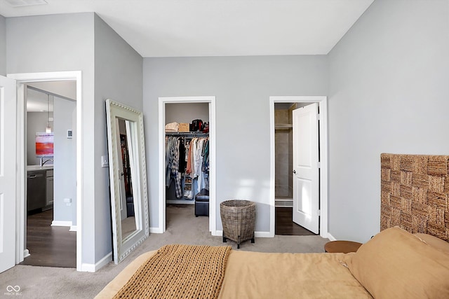 carpeted bedroom featuring ensuite bathroom, a spacious closet, sink, and a closet