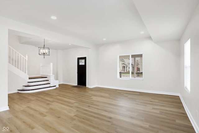 unfurnished living room with light hardwood / wood-style floors and a notable chandelier