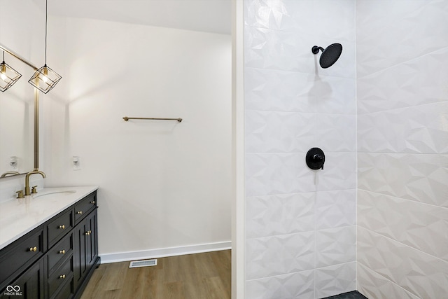 bathroom featuring vanity, a tile shower, and wood-type flooring