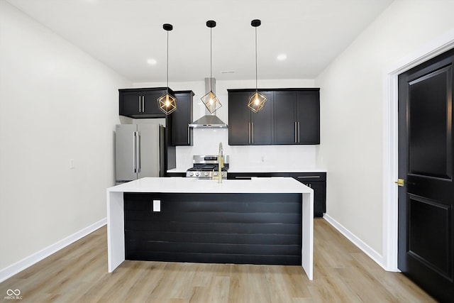 kitchen featuring stainless steel appliances, a center island with sink, hanging light fixtures, and wall chimney exhaust hood