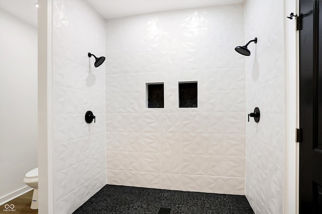 bathroom with a tile shower and toilet