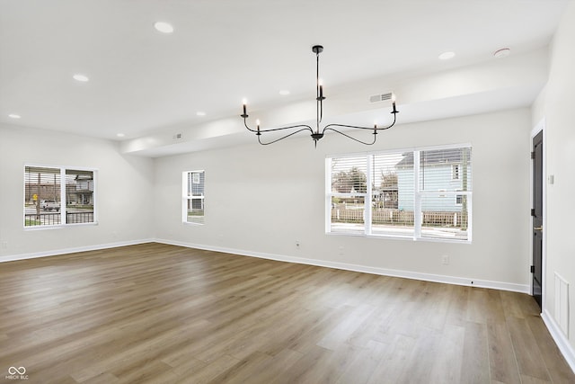 unfurnished dining area featuring a chandelier, a wealth of natural light, and light hardwood / wood-style flooring